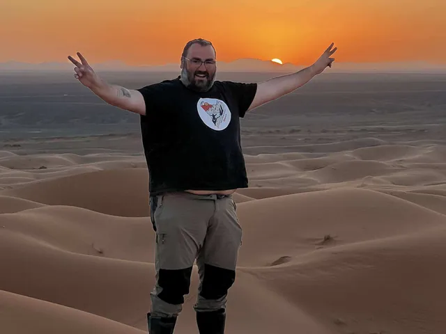 Luis con los brazos abiertos al atardecer en el desierto