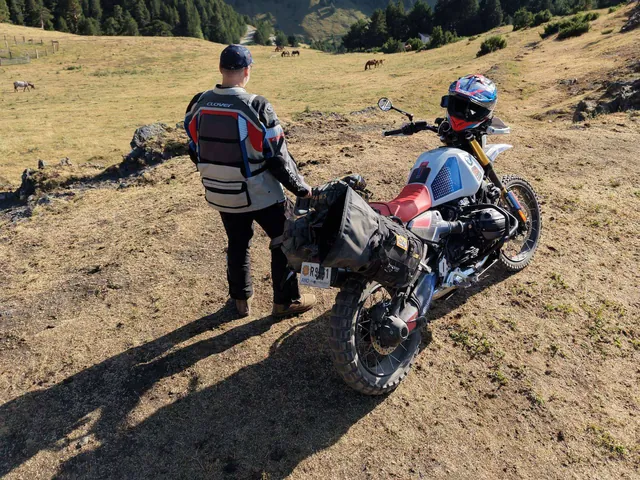 Luis junto a la moto mirando un valle de montaña