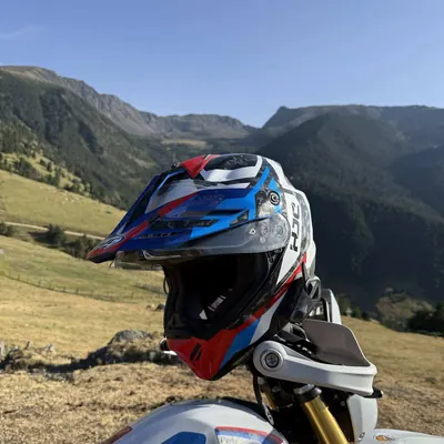 Casco apoyado en la moto con un valle de montaña detrás