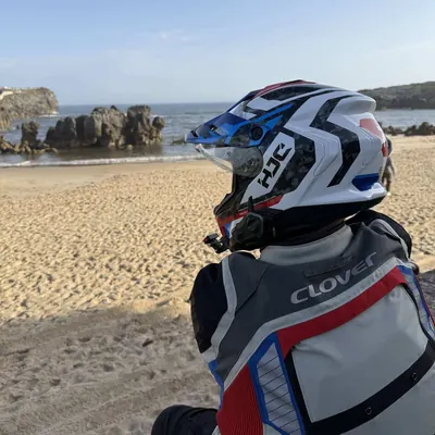 Luis sentado de espaldas en una playa de Asturias, con el casco puesto