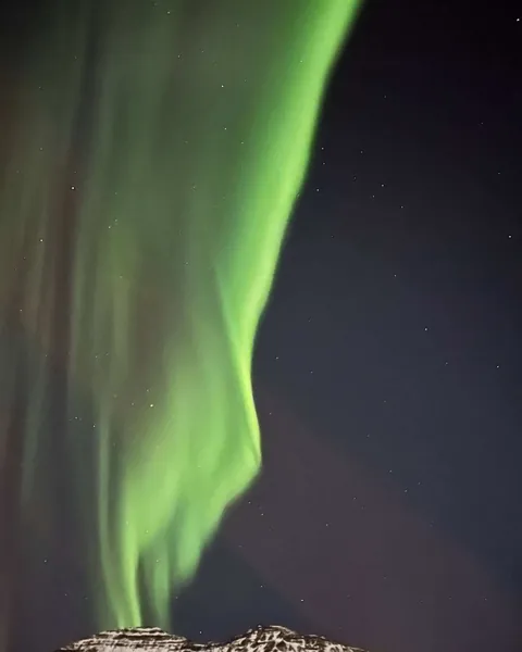 Aurora boreal verde sobre una montaña en Seyðisfjörður