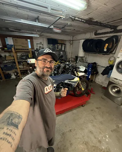 Luis haciéndose una foto en su taller, con las motos detrás