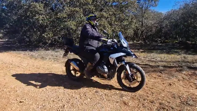 Luis rueda con la BMW R 1300 GS por una pista de tierra entre encinas, a pleno sol